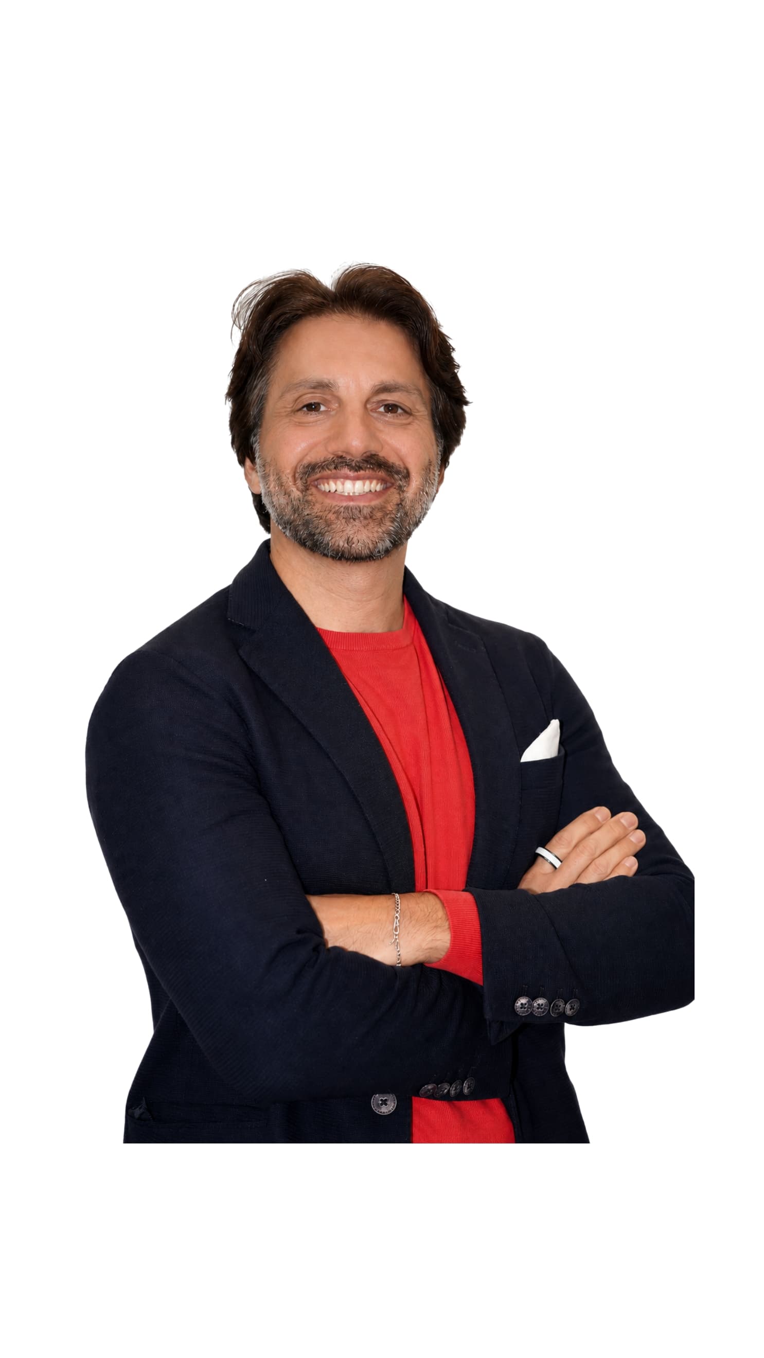 Uomo sorridente con barba, blazer blu e maglia rossa, braccia incrociate su sfondo bianco.